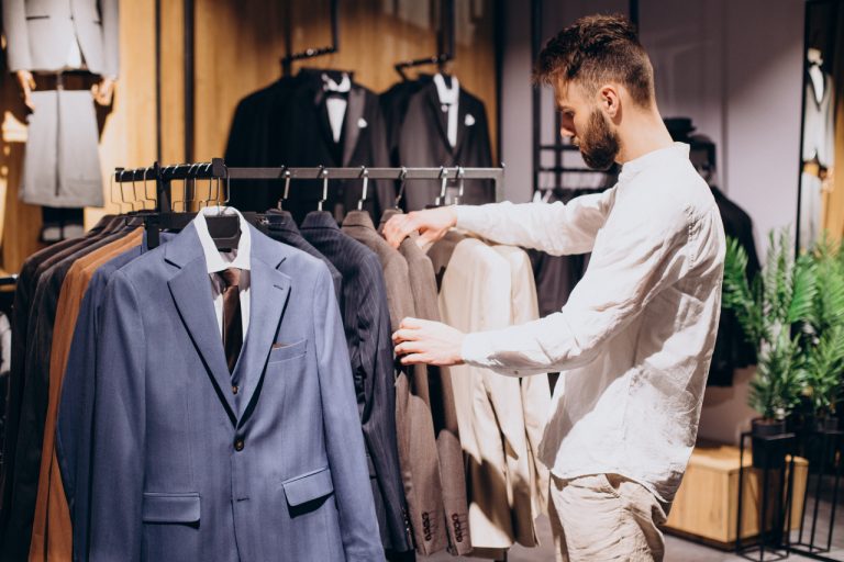 Mand ser på jakkesæt i en butik. Udvalg af jakker på bøjler.